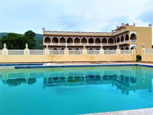 a swimming pool with a building in the background at Horizon Banquet Pushkar - with Mountain View in Pushkar