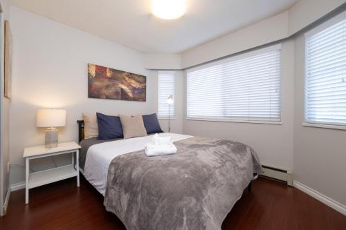 a bedroom with a bed and a table and windows at 3BR Near Commercial Dr 10 min to Downtown in Vancouver