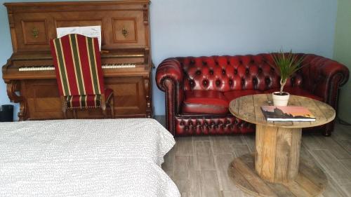 a living room with a couch and a table and a piano at La Vannerie in Béthisy-Saint-Martin