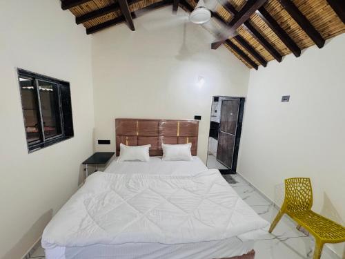 a bedroom with a white bed and a yellow chair at Ravrayhomestay in Dholovira