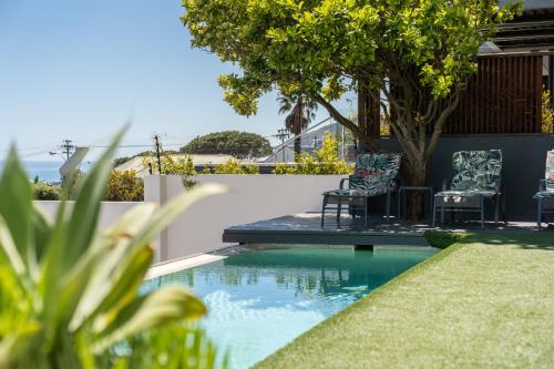 a swimming pool with two chairs and a table at Finchley Guesthouse in Camps Bay in Cape Town