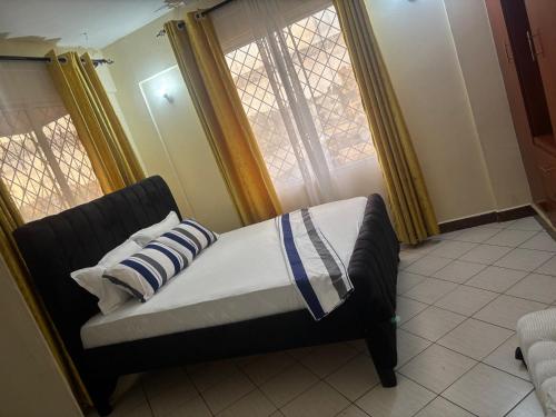 a bed in a room with two windows at AMTWAPA 2 bedroom pure blissful apartment ready to accommodate you and your family friends or colleagues in Mtwapa