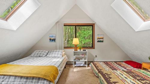 ein Schlafzimmer im Dachgeschoss mit zwei Betten und einem Fenster in der Unterkunft Hygge Home by AvantStay Deck for Outdoor Living Fire Pit Game Table in Blakeslee