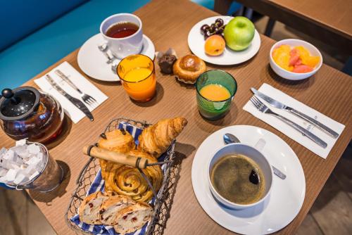 a table with breakfast foods and coffee on it at Golden Tulip Marseille Euromed in Marseille