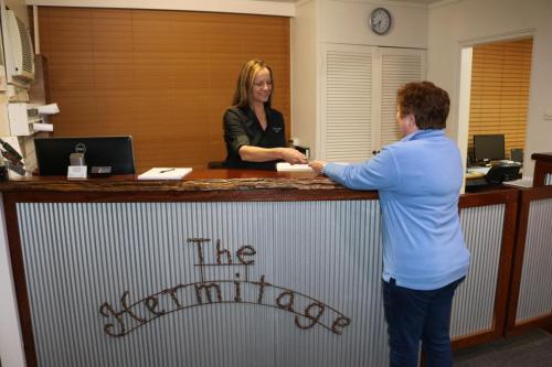 a woman standing next to a man in front of a counter at Hermitage Motel in Muswellbrook
