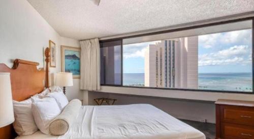 a bedroom with a large window with a view of the ocean at Marina Tower Waikiki in Honolulu