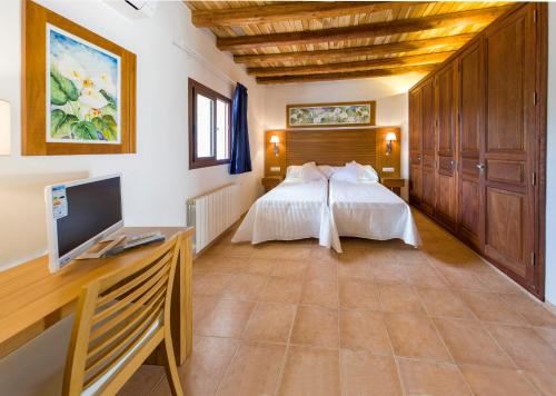 a bedroom with a bed and a desk with a computer at Can Cama in Santa Gertrudis de Fruitera