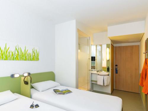 two beds in a room with a bathroom at ibis budget Zurich City West in Zürich