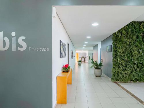 a hallway of a hospital with plants on the walls at ibis Piracicaba in Piracicaba