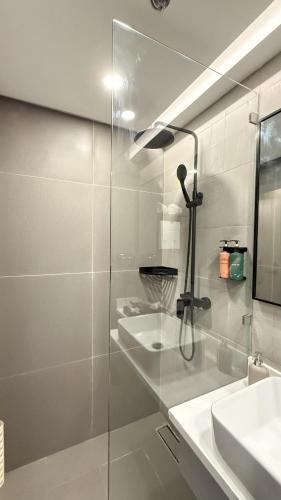 a bathroom with a glass shower with a sink at Novel Hotel Manila in Manila