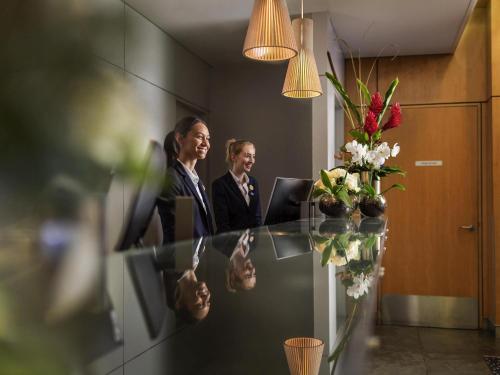 two women in an office talking in a mirror at Novotel Wellington in Wellington