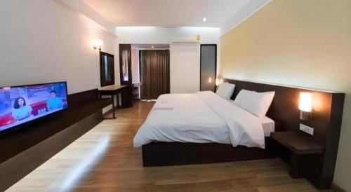 ein Schlafzimmer mit einem Bett und einem Flachbildfernseher in der Unterkunft Next Bird Suite in Bangkok