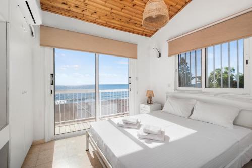 een slaapkamer met een groot wit bed en een groot raam bij Shoreline Beach House in Larnaka