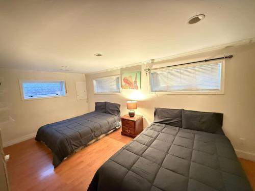 a bedroom with two beds and a table with a lamp at Downtown Central City Cozy Private 2 Bedroom Basement Suite - Independent Entry in Surrey