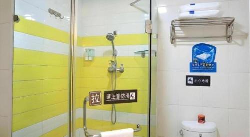 a shower in a bathroom with yellow and white stripes at 7 Days Inn Urumqi Guangming Road Beimen Metro Station in Ürümqi