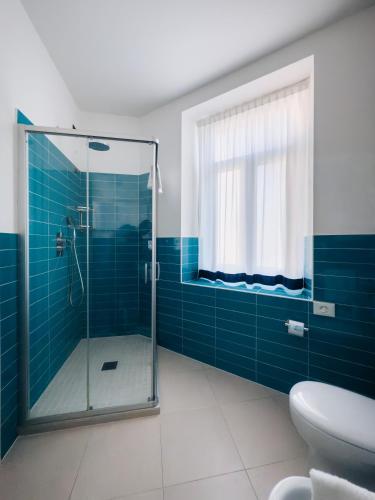 a bathroom with a glass shower with blue tiles at Hotel Villa Bernt in Grado