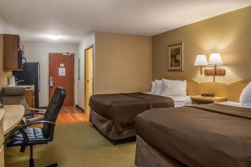 a hotel room with two beds and a chair at Suburban Studios Triadelphia - Wheeling at The Highlands in Triadelphia