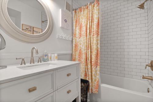 a bathroom with an orange shower curtain and a sink at Fin's Watch in Tybee Island