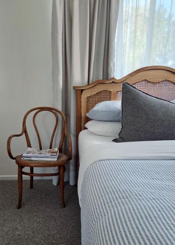a bedroom with a bed and a chair next to a window at Harrington Holiday House in Harrington