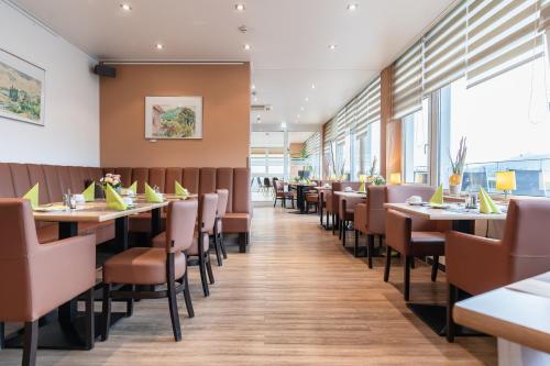 a row of tables and chairs in a restaurant at PANORAMA HOTEL in Neustadt an der Weinstraße in Neustadt an der Weinstraße