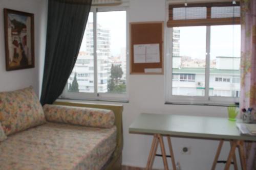 sala de estar con sofá, mesa y ventanas en Coty's Beach, habitaciones en casa compartida, en Benalmádena