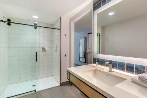 a bathroom with a shower and a sink and a mirror at Cambria Hotel Spokane Airport in Spokane