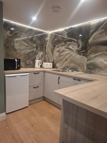 a kitchen with white cabinets and a marble wall at Tramway Apartment in Blessington