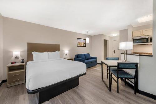 a hotel room with a bed and a desk and a kitchen at MainStay Suites Sterling near Dulles Town Center in Sterling