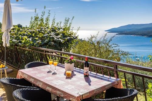 a table with two glasses of wine on a balcony at Apartment Neda in Rabac - Bay View in Rabac