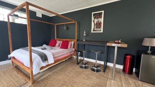 a bedroom with a canopy bed with red pillows at Villa Barry in Hout Bay