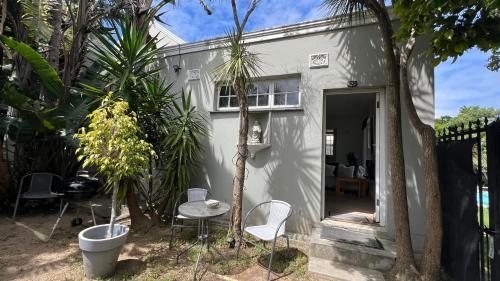 a small white house with chairs and a table at Villa Barry in Hout Bay