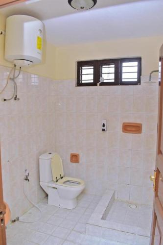 a white bathroom with a toilet and a window at Funguni Palace Hotel in Zanzibar City