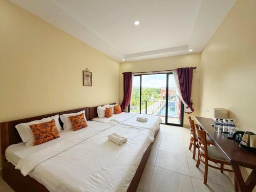 a bedroom with a large bed with a desk and a window at O Mary River Resort in Sihanoukville
