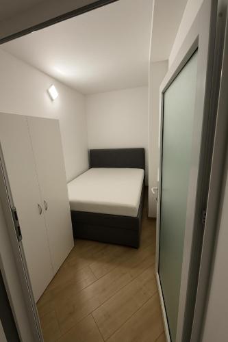 a small room with a bed and a mirror at Stan na dan Bor Apartman in Bor