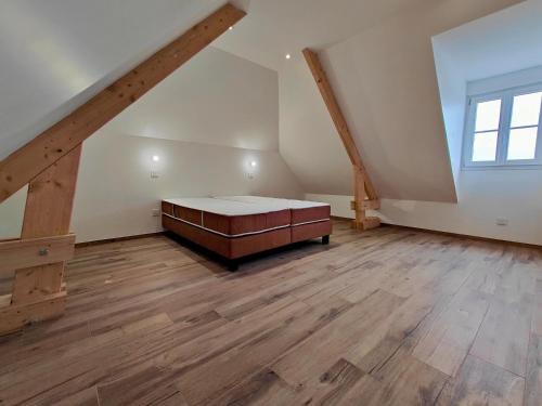 a large attic room with a bed and a window at Gite des Polders in Saint-Quentin-en-Tourmont