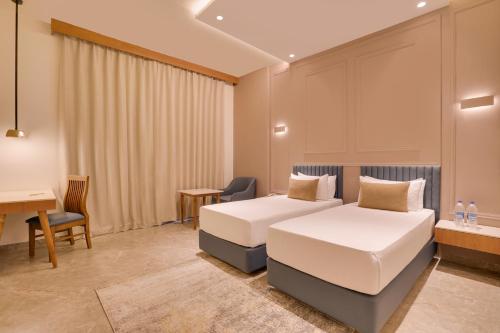 Una habitación de hotel con dos camas y un escritorio. en Lemon Tree Hotel Morbi, 