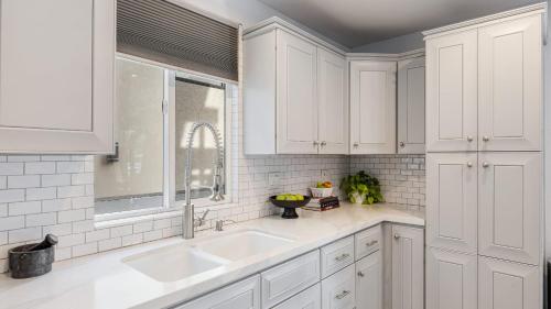 a white kitchen with a sink and a window at Sleeps 18 Steps to the Beach Shops Eateries Ocean Views Patio Fire Pit in Newport Beach