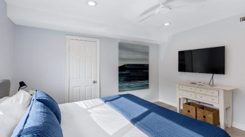 a bedroom with a bed and a flat screen tv at Sleeps 18 Steps to the Beach Shops Eateries Ocean Views Patio Fire Pit in Newport Beach