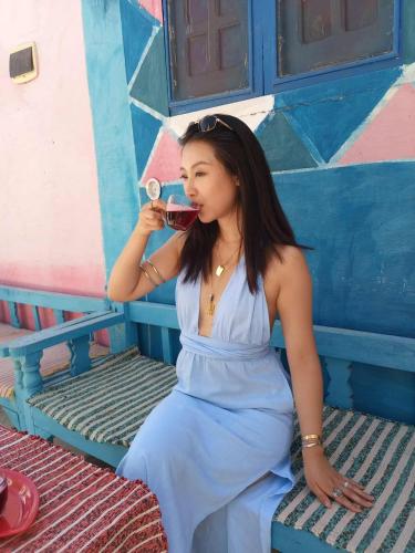a woman sitting on a bench drinking a glass of wine at Kamel House in Aswan