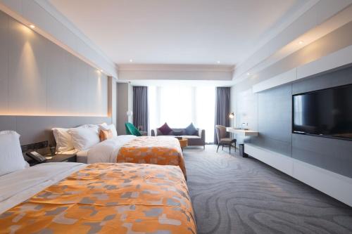 花都にあるZhengsheng Honggu Hotel - Guangzhou Sunac Cultural Tourism City Huadu Plazaのベッド2台と薄型テレビ付きのホテルの部屋