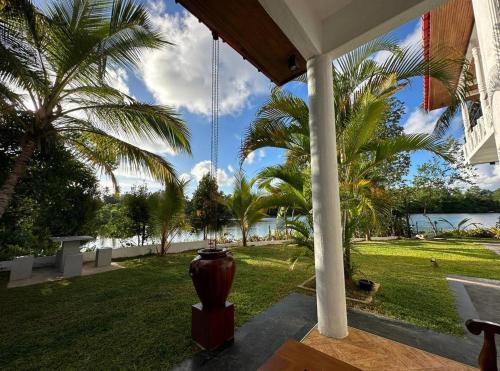 a porch with palm trees and a view of the water at Riverview Bentota in Bentota