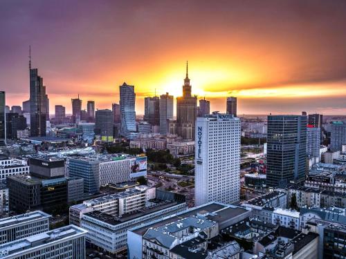 a view of a city skyline with the sun setting at Novotel Warszawa Centrum in Warsaw