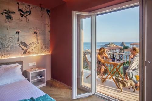 a man and a woman sitting at a table on a balcony at Drea Acitrezza Luxury Home in Acitrezza