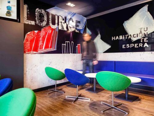 Una habitación con mesas y sillas verdes y azules. en Ibis Budget Barcelona Sant Andreu De La Barca, en Sant Andreu de la Barca