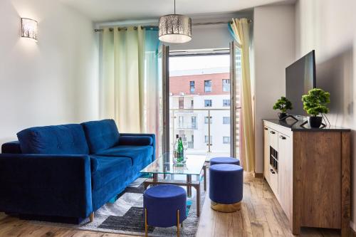 ein Wohnzimmer mit einem blauen Sofa und einem Fenster in der Unterkunft Apartament Szafirowy Paderewskiego 47a Dzielnica Parkowa Rzeszów in Rzeszów