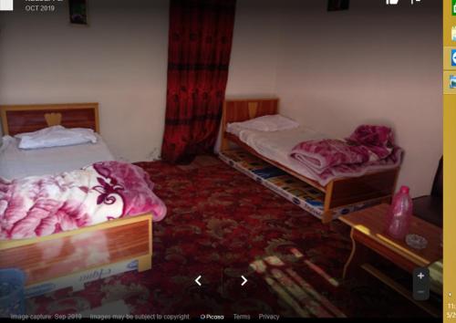 a room with two beds and a table in a room at Malik Guest House in Dargai