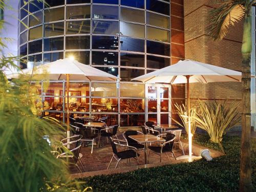 a restaurant with tables and umbrellas in front of a building at Mercure Sao Paulo Jardins in Sao Paulo