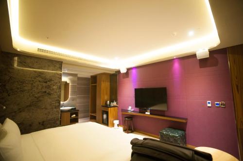 a hotel room with a bed and a flat screen tv at LE LE Motel in Pingtung City