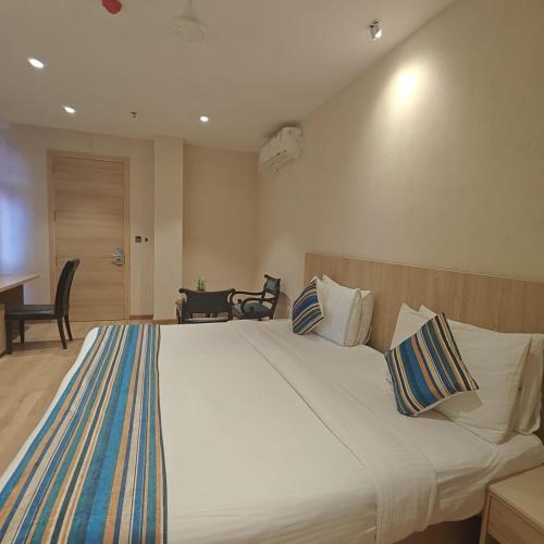 a bedroom with a large white bed with striped pillows at Bluestone Prime by The Cosy Hotels in New Delhi