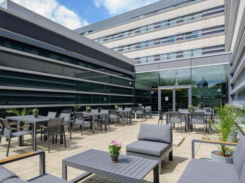 a patio with tables and chairs in front of a building at Novotel Aachen City in Aachen